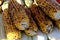 Top view of kitchen table with grilled sweet corn cob under melting butter and greens on baking paper