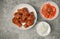 Top view Korean spicy deep-fried chicken topped white sesame with kimchi and pickled radish side dishes on the gray concrete table