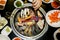 Top view of Korean style barbecue, assorted meat and seafood grilling over table top charcoal stove with various seasoning and