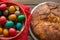 Top view of a Kozunak Traditional Easter sweet bulgarian bread and colored eggs in a red wicker basket