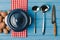 top view of ladles, knife, pan and uncooked potatoes on blue table