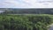 Top view of lake in forest. Clip. Landscape panorama of forest with swampy areas. On horizon near coast of lake is town