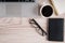 Top view of laptop and notepad with glasses and pocketbook on wood desktop and cup of coffee.