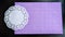 Top view of lilac or purple sheet of velvet paper and white openwork carved napkin. Abstract frame, background and