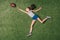 Top view of little sportive girl catching rugby ball on grass,