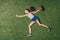 Top view of little sportive girl throwing rugby ball on grass,