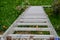 Top view of a long silver aluminum ladder leaning against the wall of the house. Close up view from top of tall step ladder