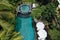 Top view of luxury round pool with white umbrellas and sun beds in tropical jungle and palm trees. Luxurious villa