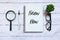 Top view of magnifying glass,glasses,plant,pen and notebook written with Know How on white wooden background.
