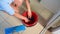 Top view maid pouring cleaner detergent into a red bucket, for washing and mopping the floor while cleaning the house.