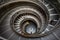 Top view of a majestic spiral staircase with multiple people ascending and descending in the Vatican