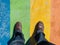 Top view of male feet on a rainbow colored sidewalk- LGBTQ concept