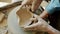 Top view of male and female hands making heart shape bowl in pottery studio