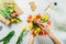 Top view male florist hands making spring bouquet using tulips at workspace with recycled wrapping materials. Learning flower