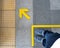 Top view of man feet standing over Arrow symbol on subway platform. Yellow arrow sign on floor at the train station