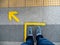 Top view of man feet standing over Arrow symbol on subway platform. Yellow arrow sign on floor at the train station