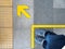 Top view of man feet standing over Arrow symbol on subway platform. Yellow arrow sign on floor at the train station