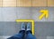 Top view of man feet standing over Arrow symbol on subway platform. Yellow arrow sign on floor at the train station