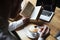 Top view of man in white shirt stirring coffee while reading boo