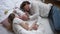 Top view man and woman lying with newborn boy on white soft bed at home resting. Happy Caucasian father mother and