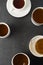 Top view of many cups, mugs with hot tea drink on dark background, copy space. Tea time or tea brake. Autumn beverage. Toned image