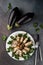 Top view many stuffed eggplant rolls with meat and vegetables on a white plate on grey cement background with cutlery, concept of