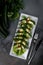 Top view many stuffed zucchini rolls with meat and vegetables on a white plate on grey cement background with cutlery, concept of