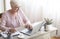 Top view of mature working lady making notes, using laptop