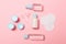 Top view of means for face care: bottles and jars of tonic, micellar cleansing water, cream, cotton pads on pink background.