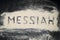 Top view of MESSIAH word written on white sand