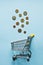 Top view mini shopping cart with Coins on blue table.