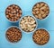 top view of mixed nuts in shell and without shell in bowls almond hazelnuts and peanuts on blue background