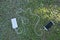 Top view of mobile phone equipment placed on the grass power bank and charging cable