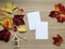 A top view mockup with red autumn boston ivy leaves, a little house Christmas decoration, blank cards on the wooden background