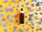 Top view of mockup of unbranded brown plastic spray bottle and petals of blue hydrangea flowers on a textured bright orange yellow