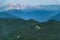 Top view of the mountain range and peaks covered with snow. Low buildings on the crest of a mountain range