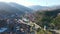 Top view of mountain valley city. Footage. Long city in mountain valley on sunny spring day. Modern city is located in