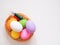Top view, Multi colored eggs in basket on a white wooden background