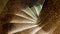 Top view of a narrow stone spiral staircase lined with ceramic brown tiles