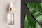 Top view of Natural essential oil, serum glass drop bottle on a marble background wit green leaves. Alternative medicine, aromatic