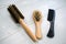 Top view of natural wooden hairbrushes with handle and plastic comb isolated on a wood background.