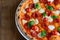 Top view of neapolitan pizza with pepperoni, mozzarella and cherry tomatoes on a white plate. Close up. Macro.