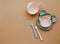 Top view neutral baby cute tableware on brown background, flat lay