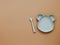 Top view neutral baby tableware on brown background