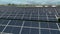 Top view of a new solar farm. Rows of modern photovoltaic solar panels next to the green field.