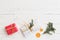 Top view on nice Christmas presents decorated with ribbons, tree branch and orange slices on white wooden background