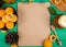 top view of note pad with apricots compote jam and pinecone on green background with copy space