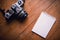 Top view of notebook paper and camera on Office desk table.