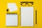 Top view of Notebooks, pens, glasses, business card, paper clip  on yellow background and copy space