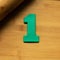 Top view of the number one made from green plasticine on a wooden table